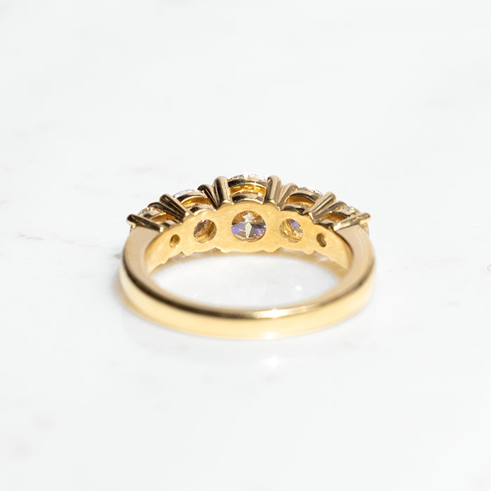 A five stone diamond ring with a central diamond flanked by four smaller diamonds, set in 18k yellow gold.