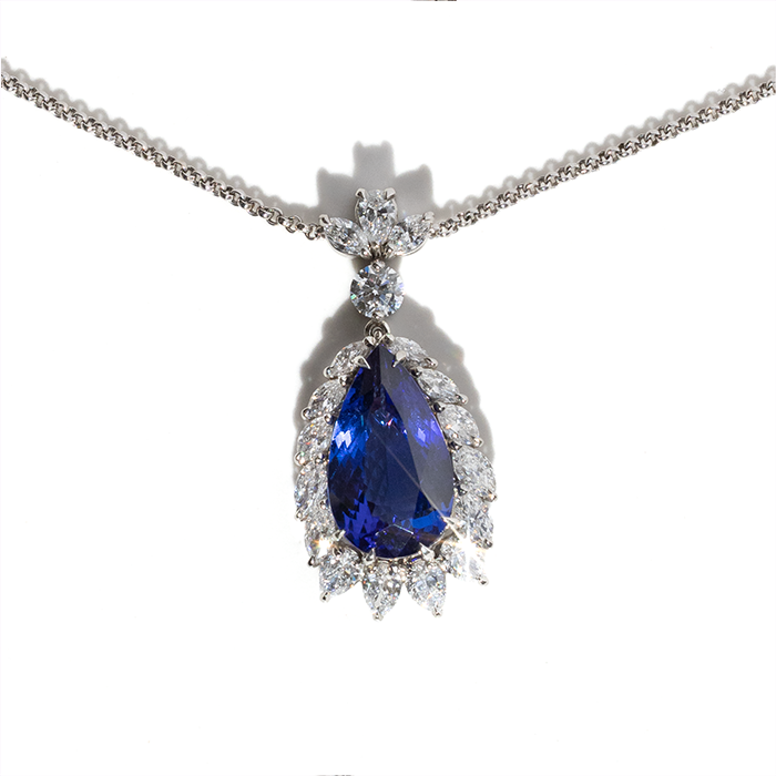 A blue tanzanite pendant necklace with a chain, encrusted with diamonds.
