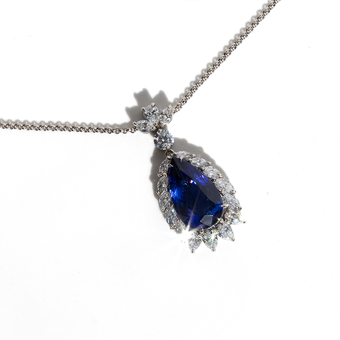 A blue tanzanite pendant necklace with a chain, encrusted with diamonds.