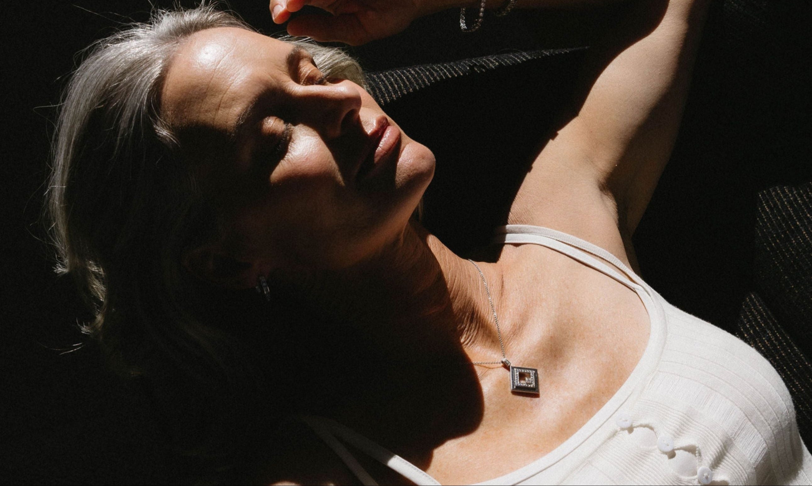 Woman with a necklace lying on a dark surface