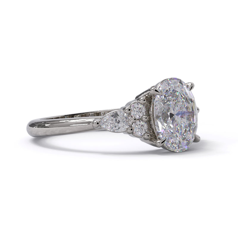 A white gold or platinum engagement ring featuring a large central diamond with 3 smaller diamonds on each side, set against a white background.