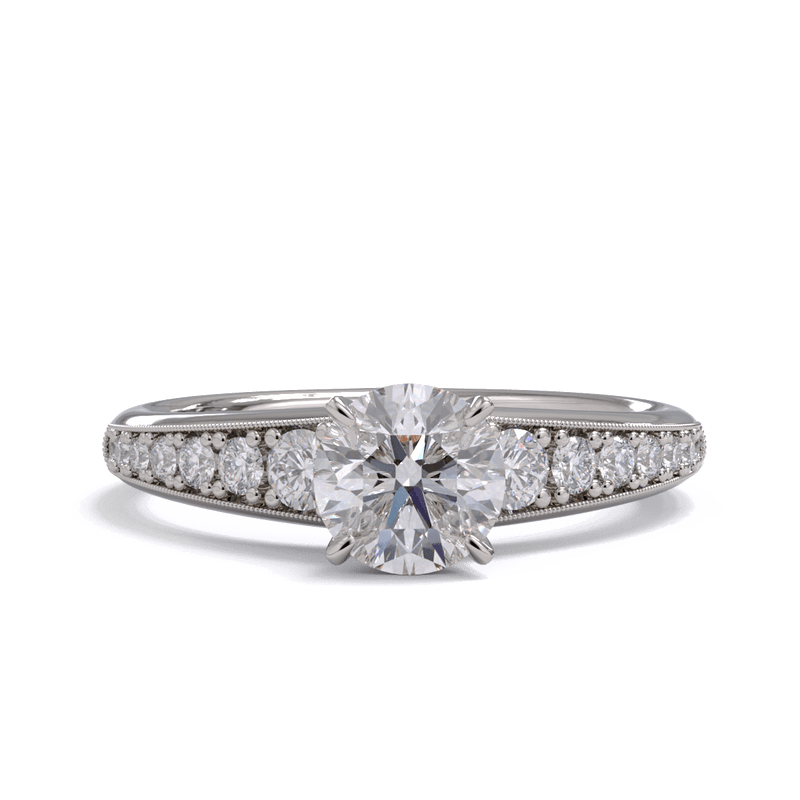 A white gold or platinum round brilliant diamond solitaire ring with smaller diamonds along the band.