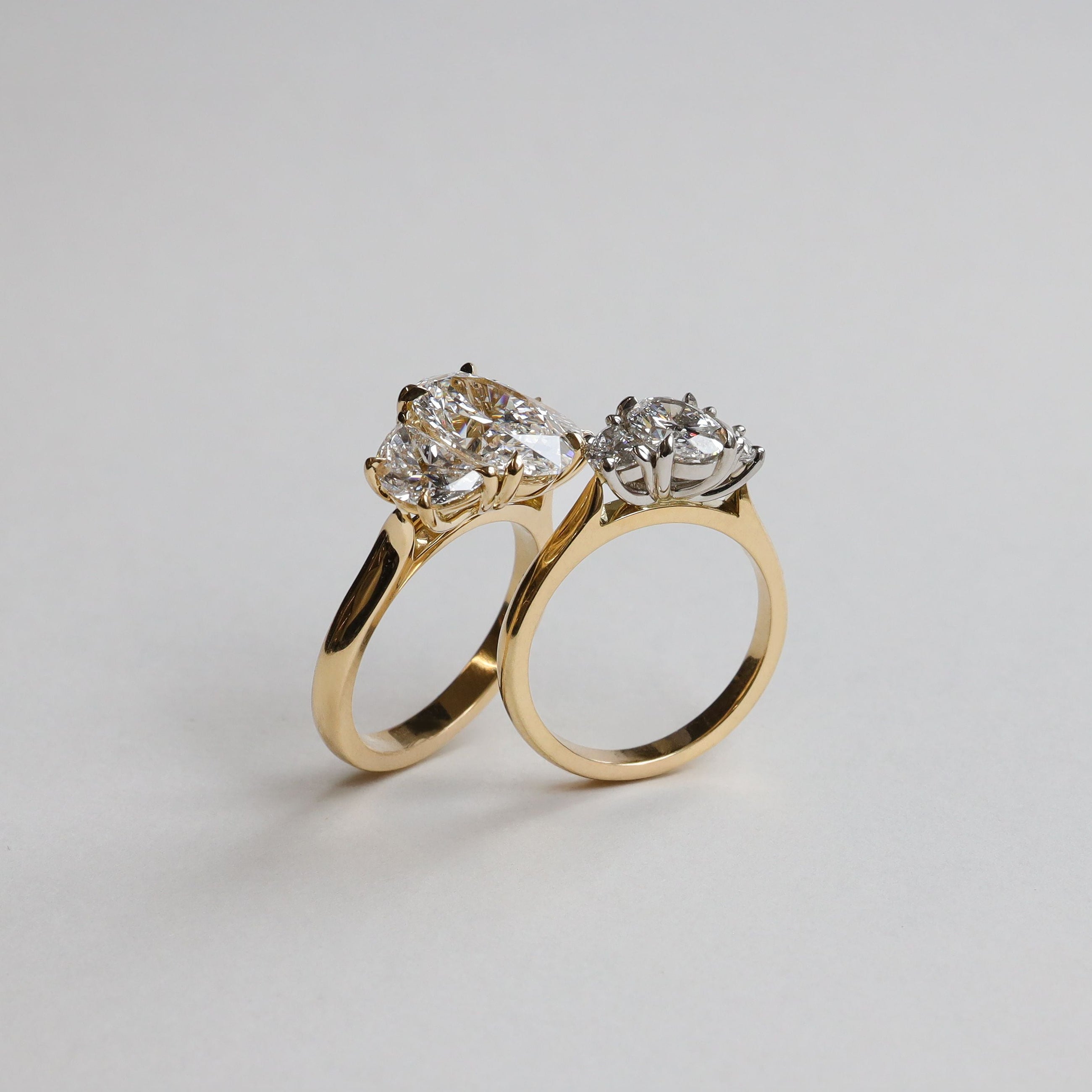 Two gold engagement rings with diamond stones on a light gray background. Handmade in New Zealand