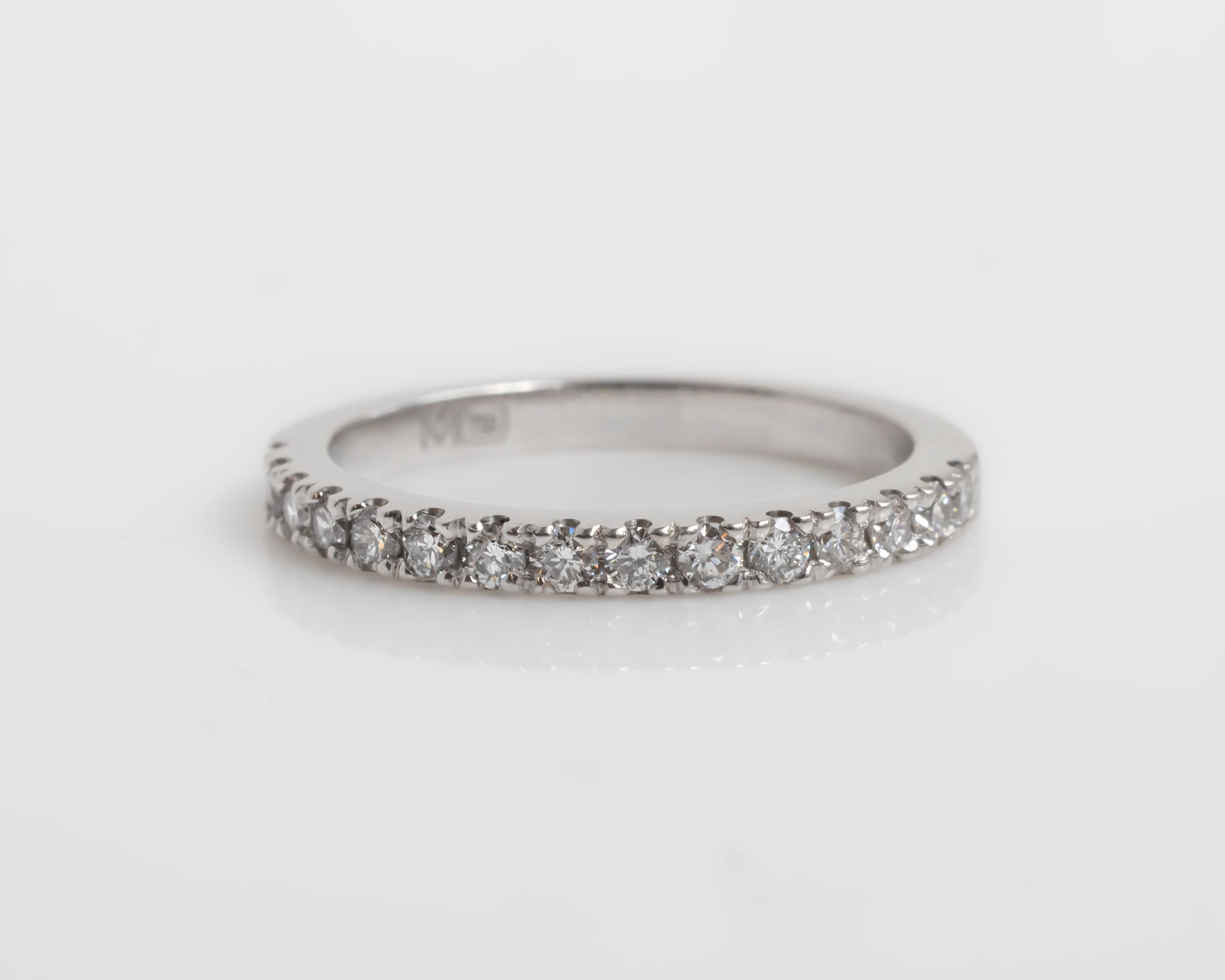 White-gold ring with small diamonds on a light gray background