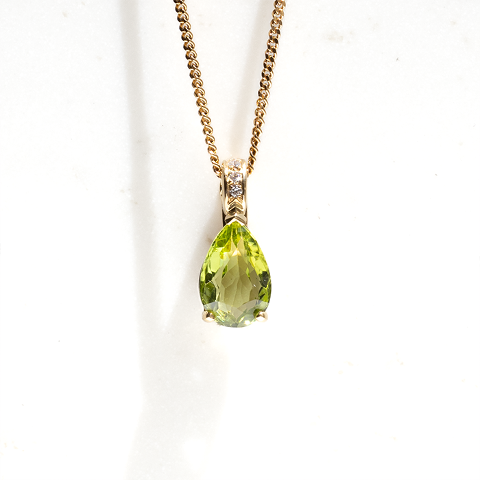 A pear-shaped peridot pendent set in 18ct yellow gold and finished with pave round brilliant diamonds on the clasp. Handmade by our Master Jewellers.