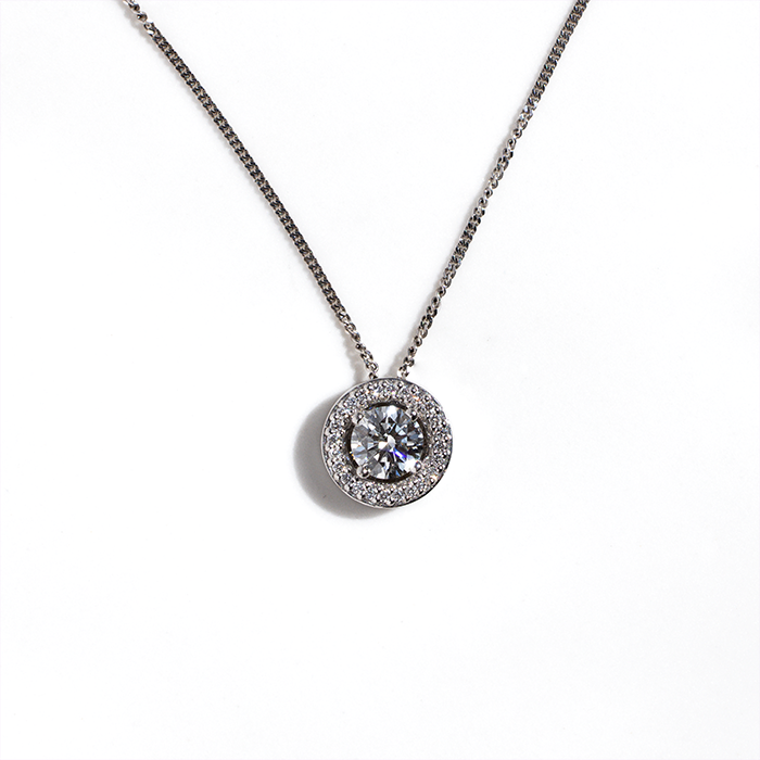 A round-cut diamond pendant necklace with a white gold metal chain.