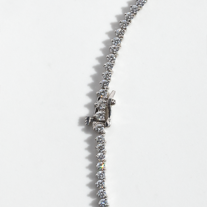 A tennis necklace featuring a row of round-cut diamonds set in white gold, displayed against a white background.