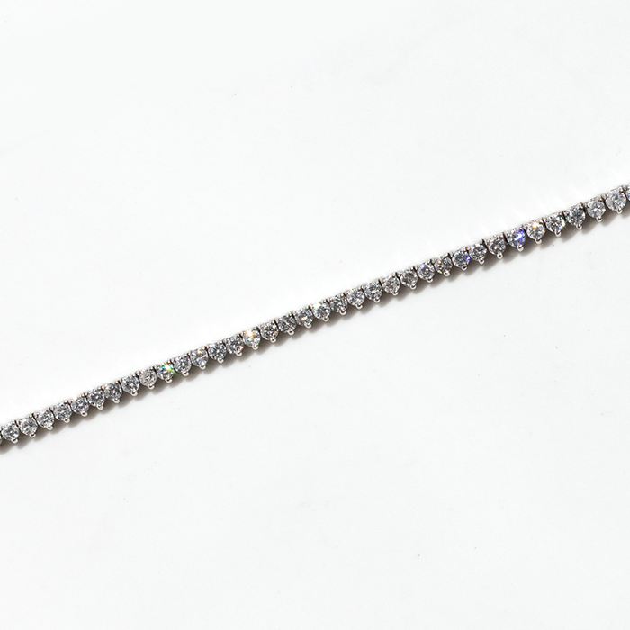 A tennis necklace featuring a row of round-cut diamonds set in white gold, displayed against a white background.