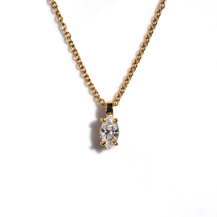 A gold diamond pendant necklace with a simple design, featuring a marquise-cut diamond.