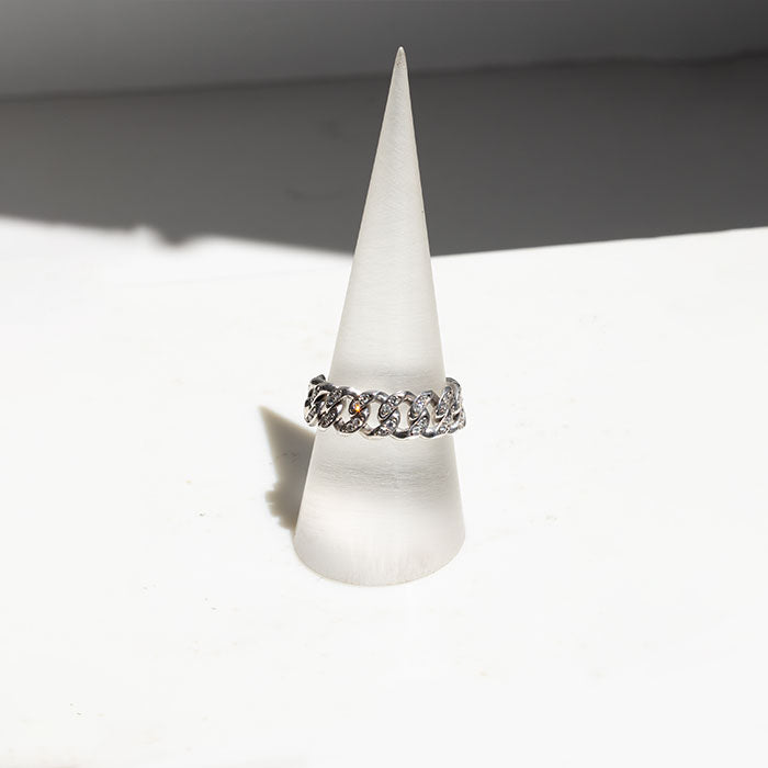 A Merida Diamond Chain Ring with a flexible chain design, adorned with round brilliant cut diamonds, displayed on a white cone-shaped stand against a white background.