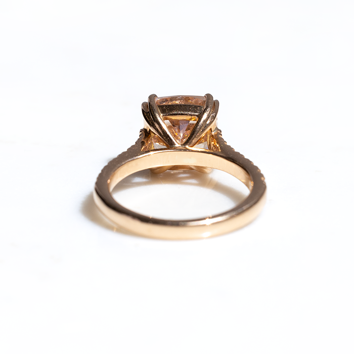 back vewi of a cushion cut pink diamond ring with smaller round brilliant cut diamonds on the band, set in an 18ct rose gold.