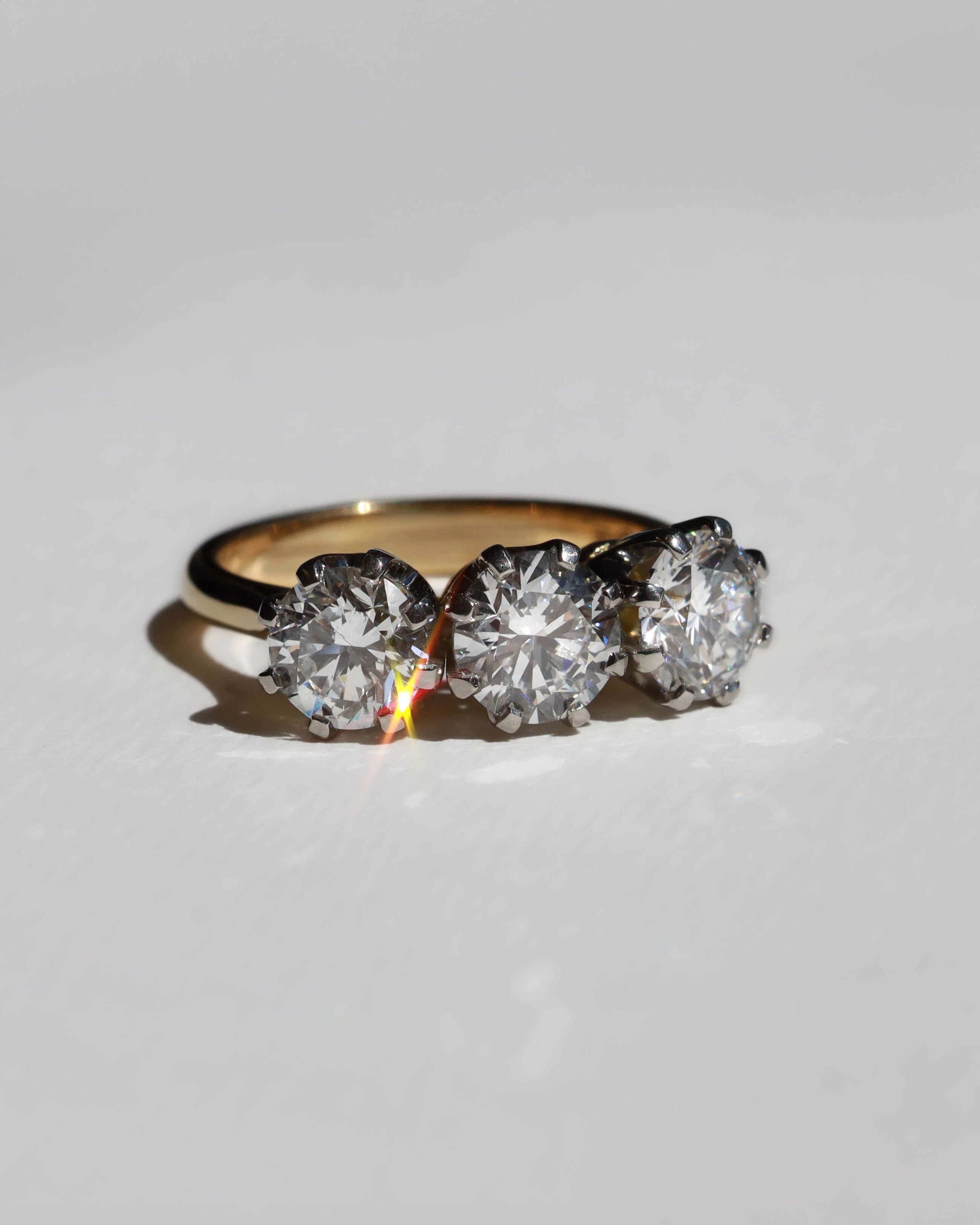 Gold diamond engagement ring with three diamonds on a light gray background. Made in Auckland, New Zealand
