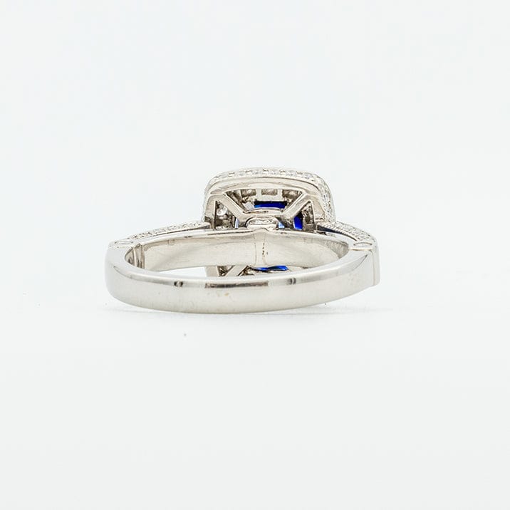 Back angle of a Sapphire and Diamond Halo Engagement Ring with a cushion cut blue sapphire center stone, encircled by round diamonds set in a platinum band.
