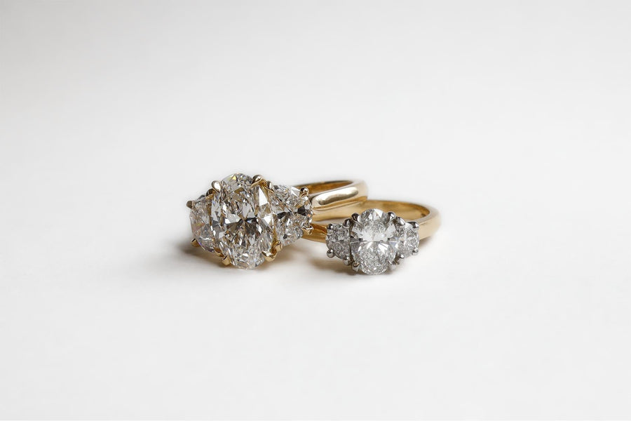 Two diamond rings that feature an oval center stone and two hald moons. One is made in Gold and the other in Platinum and Gold 