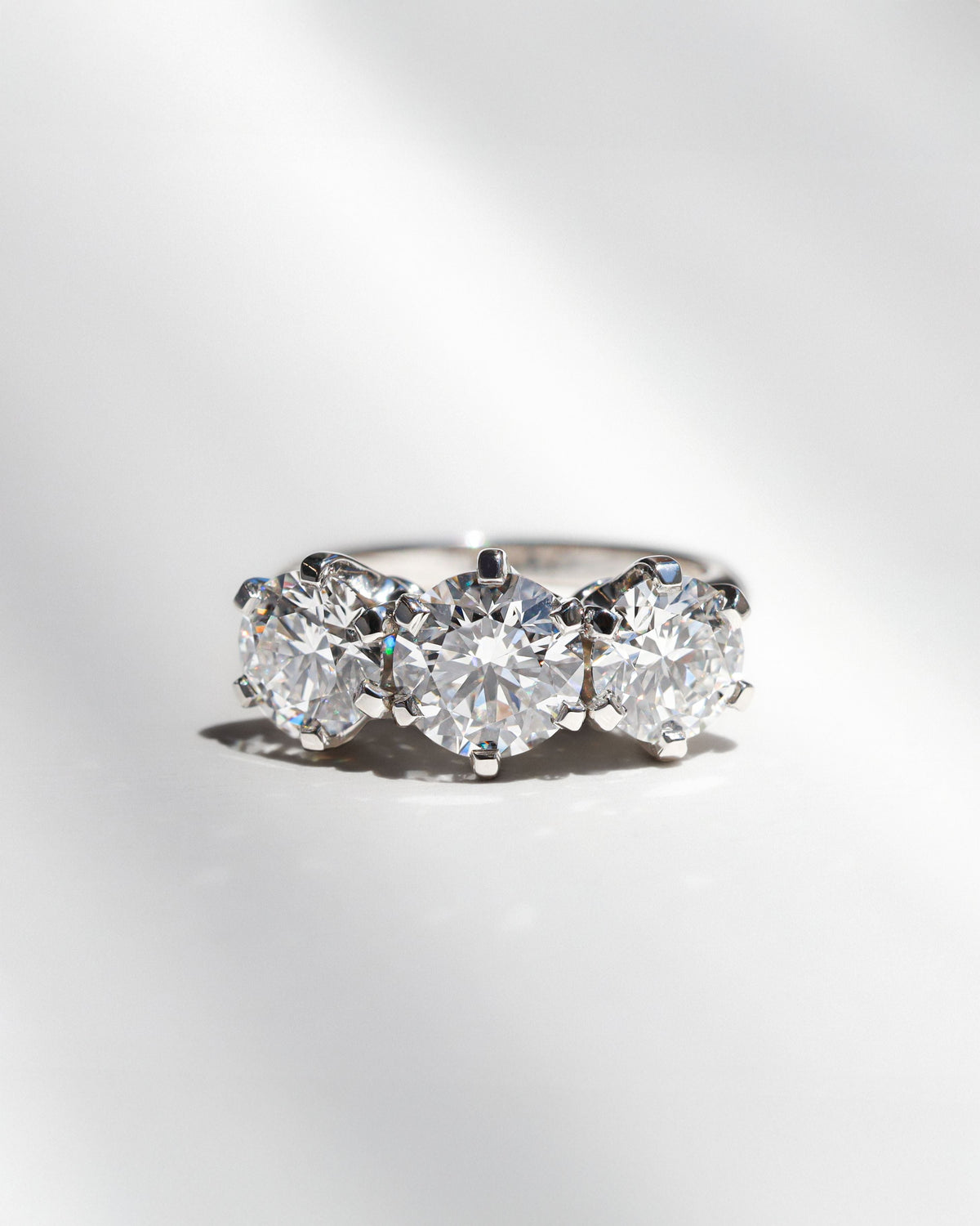 Three stone round diamond engagement ring on a white background. 
