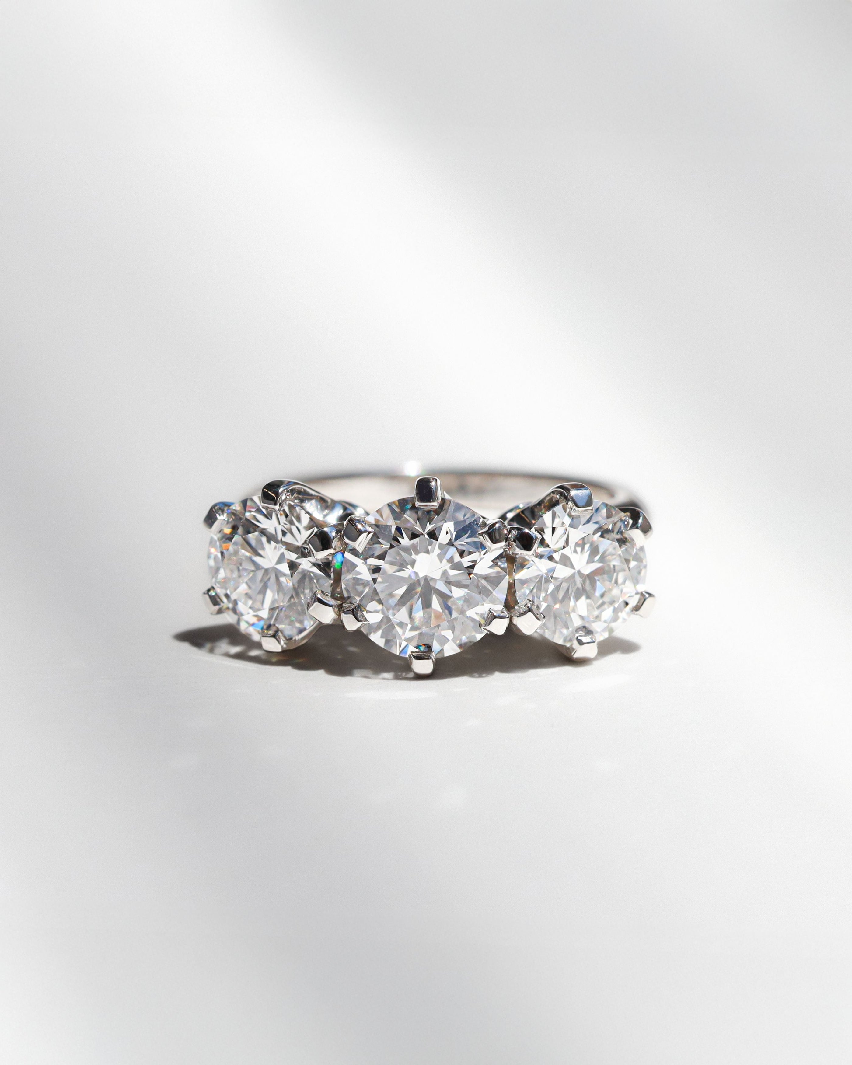Three stone round diamond engagement ring on a white background. 