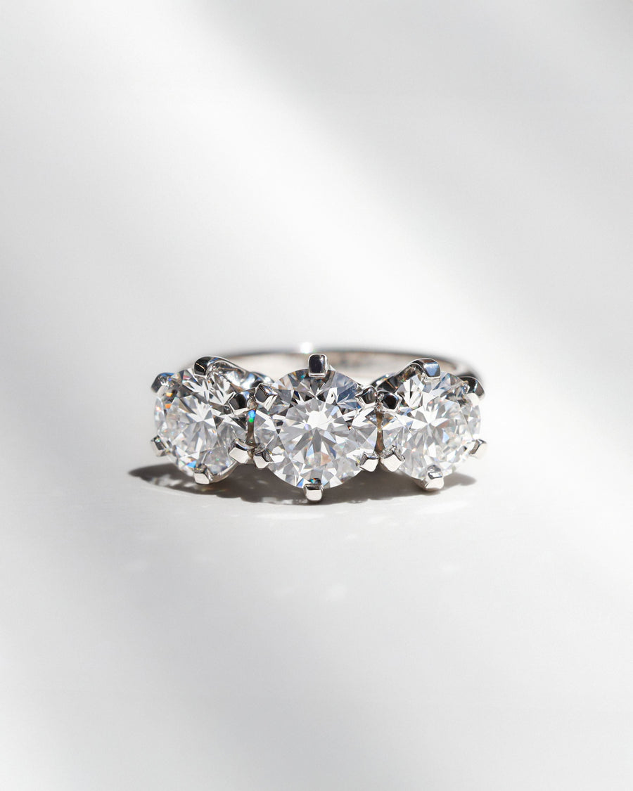 Three stone round diamond engagement ring on a white background. 