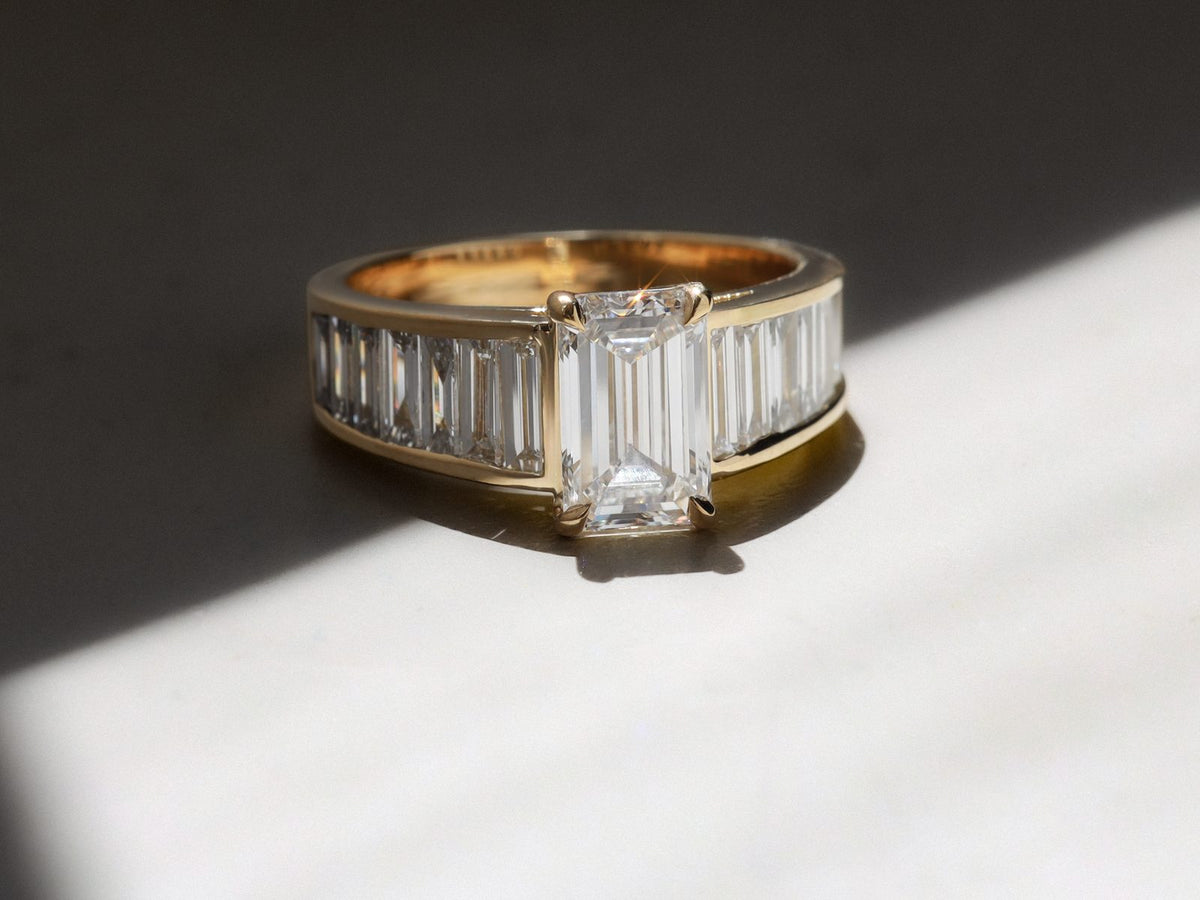 Gold ring with an emerald-cut centre diamond and baguette-cut side diamonds