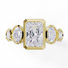 Yellow Gold ring with a central emerald-cut diamond flanked by two oval diamonds. Bezel set in a low profile. Top view