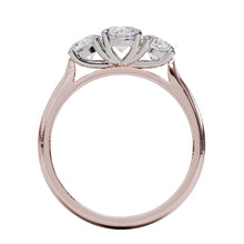 A three-stone diamond ring with a rose gold band and platinum setting for the diamonds.