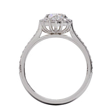 A gold diamond ring with a large round central diamond surrounded by a halo of smaller round diamonds. Set in platinum on a platinum or white gold band with pave down on the band, displayed against a white background.