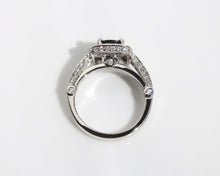 Handmade ring featuring a blue sapphire centre stone, surrounded by a halo of diamonds, with a pavé diamond band.