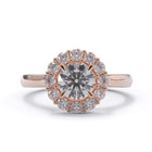 Rose gold ring with a large diamond and smaller diamonds around on a white background