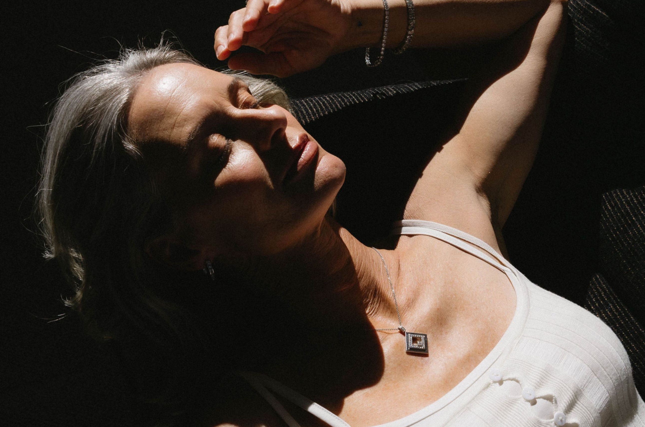 Woman with a necklace lying on a dark surface