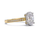Gold ring with a large diamond and smaller diamonds on the band against a white background