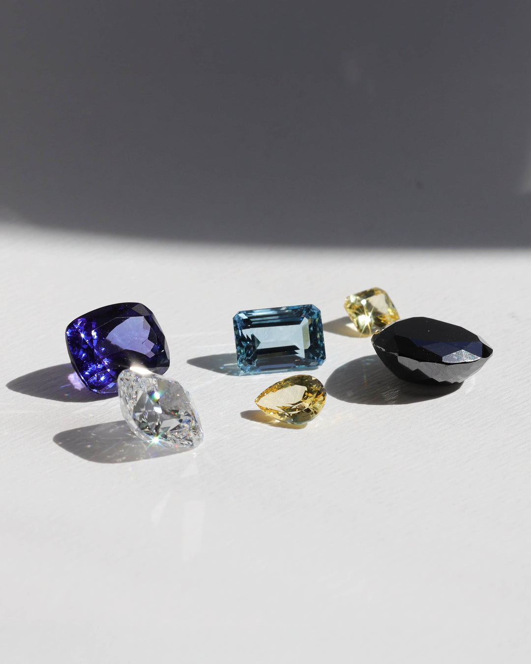 Collection of various gemstones on a light surface with a dark background. 