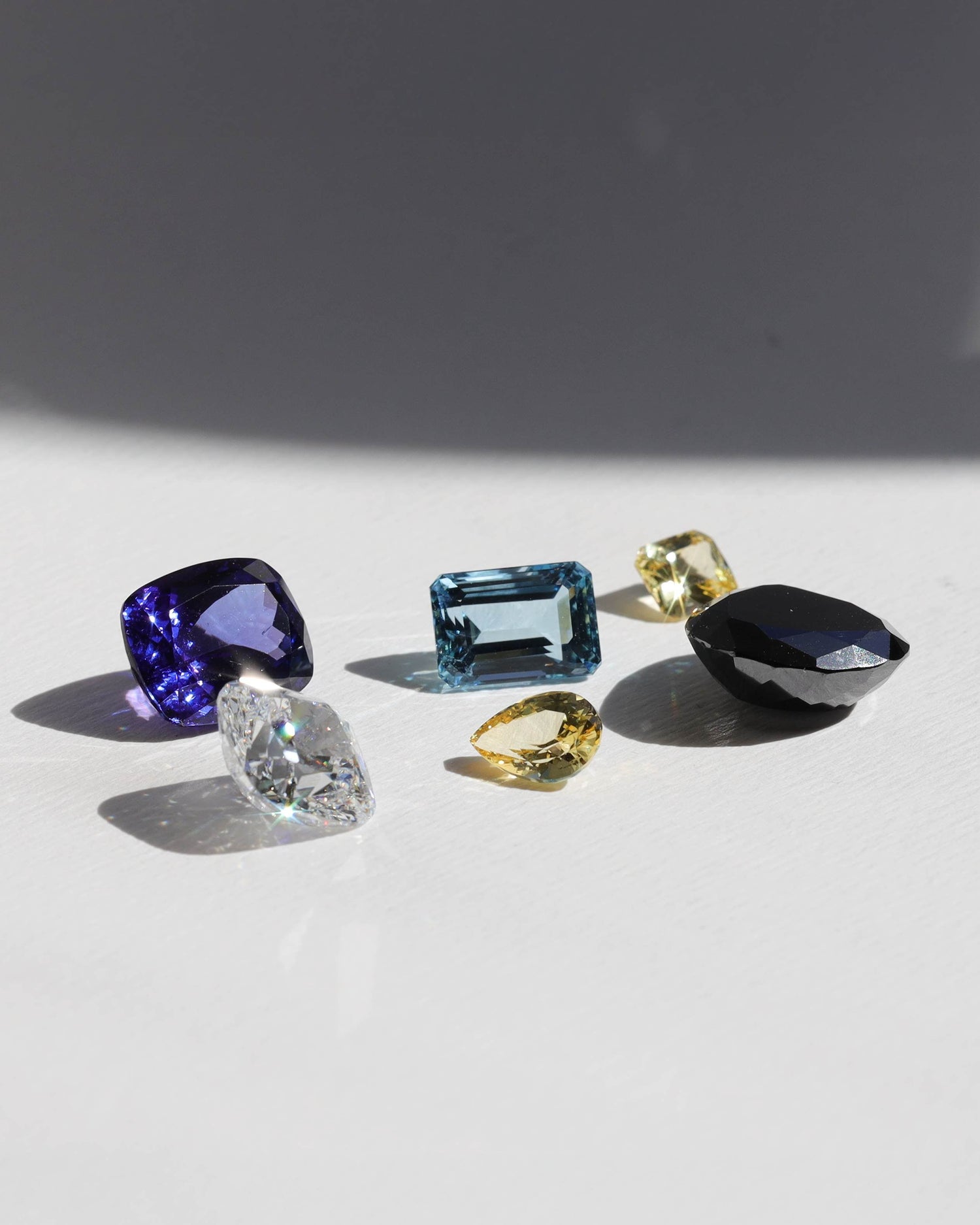 Collection of various gemstones on a light surface with a dark background. 