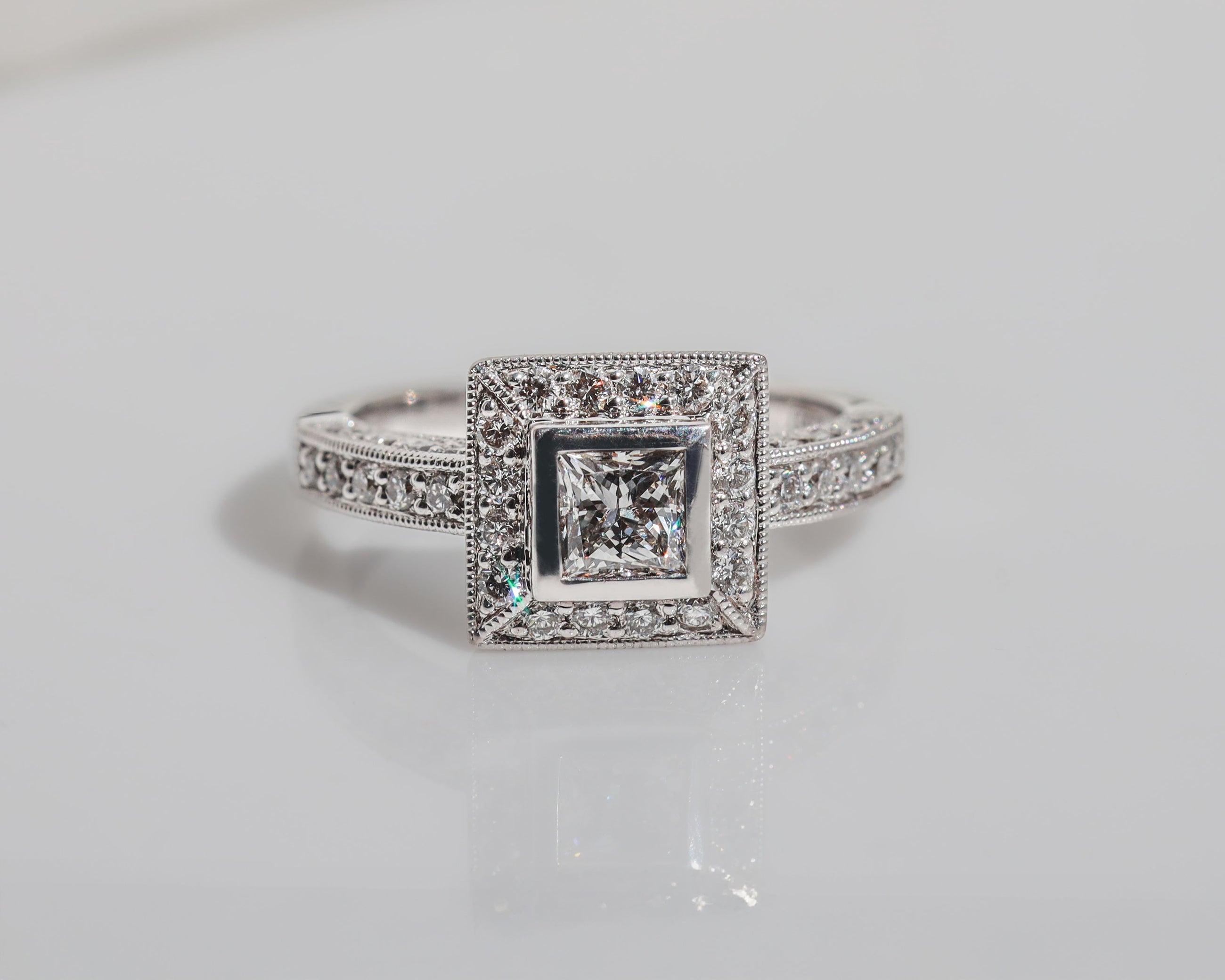 Front view of a diamond engagement ring featuring a halo of diamonds around the centre stone and rows of diamonds along the band.