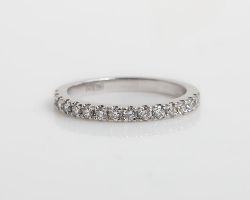 White-gold ring with small diamonds on a light gray background