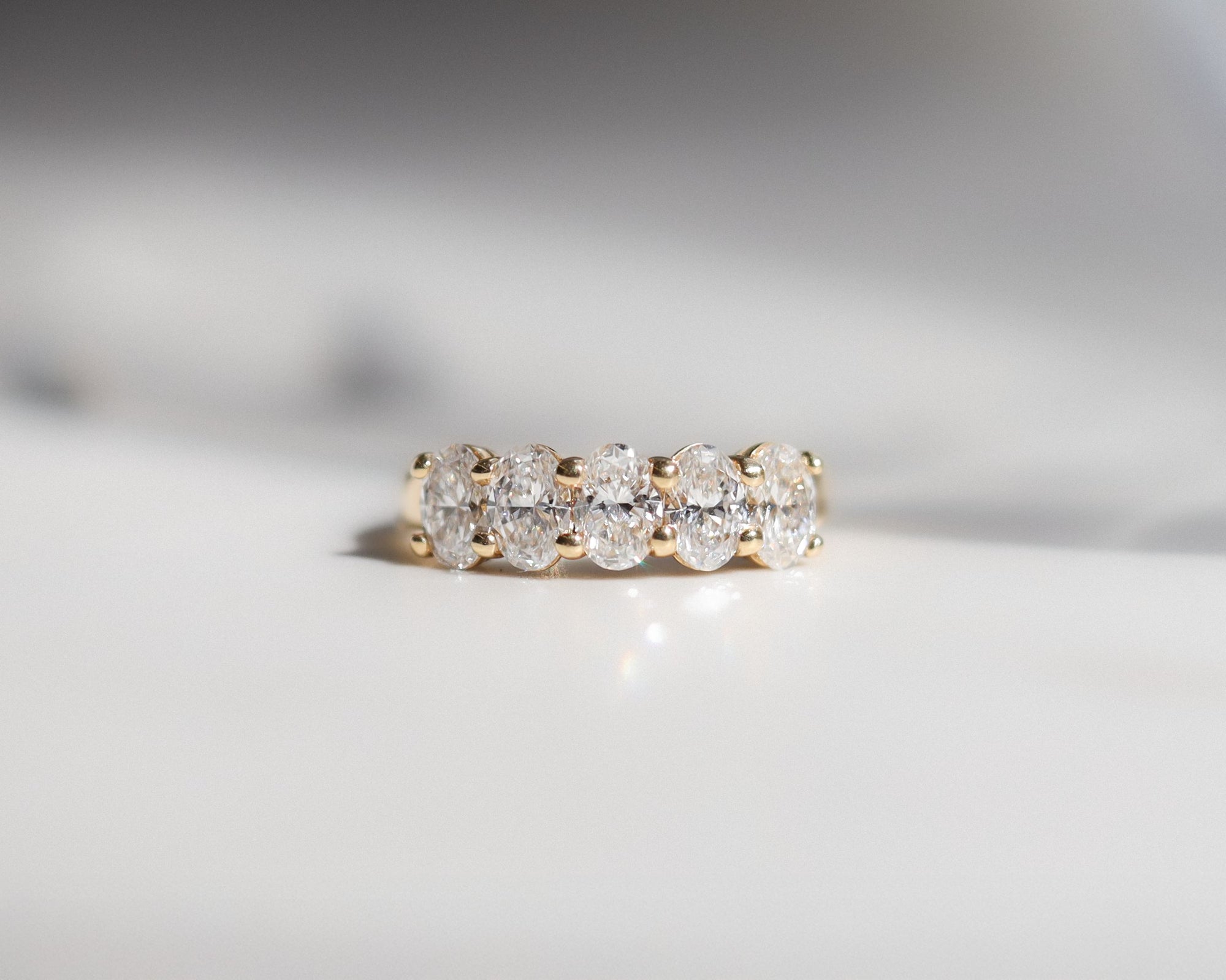 Gold ring with diamonds on a light gray background