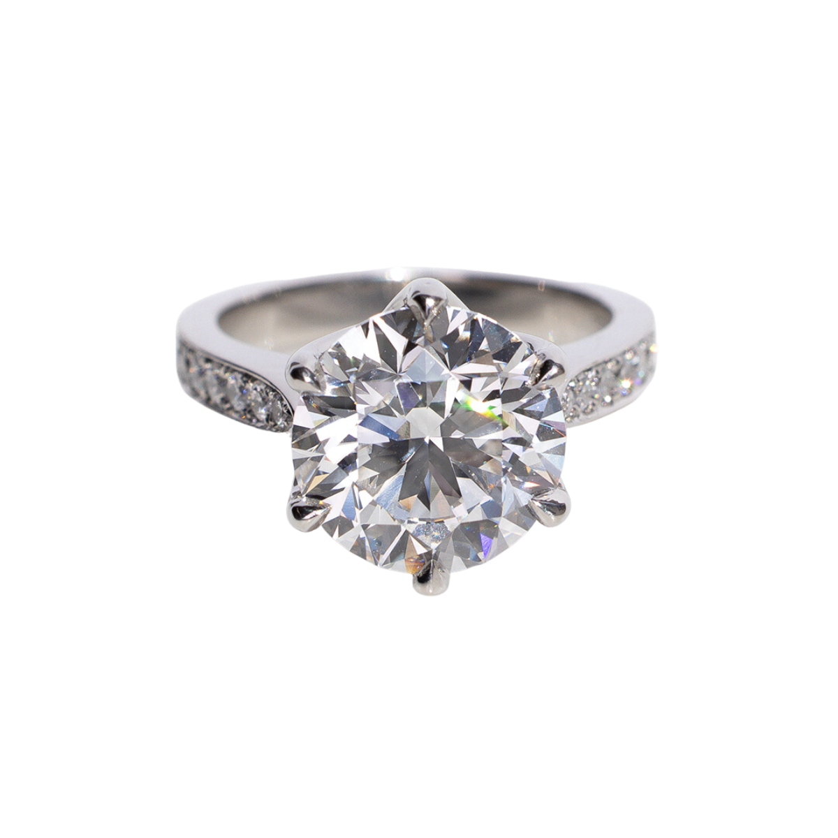 A custom designed platinum, five carat diamond engagement ring with six prongs. The ring's band features a smaller diamond pave design.   