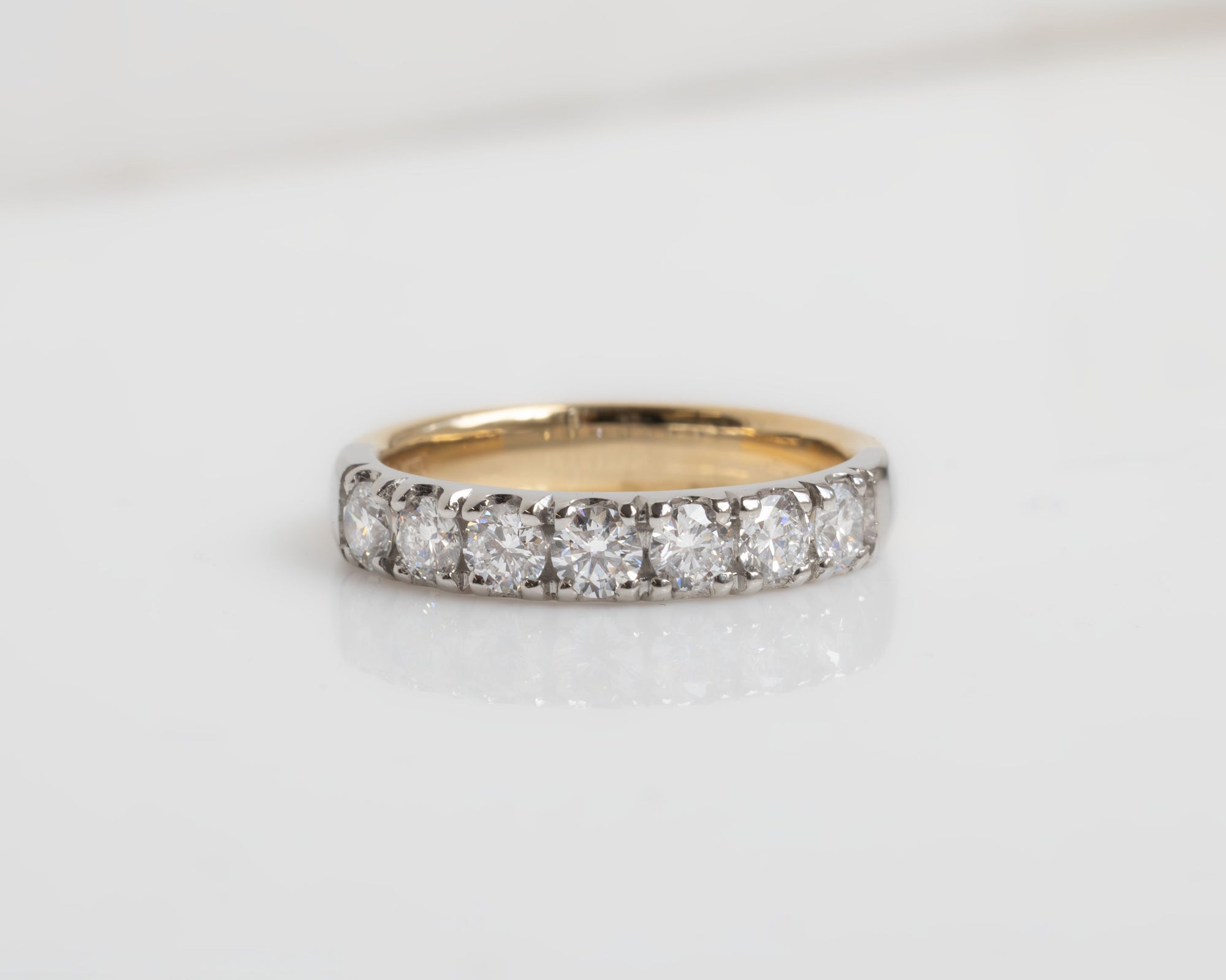 Gold ring with diamonds on a light gray background