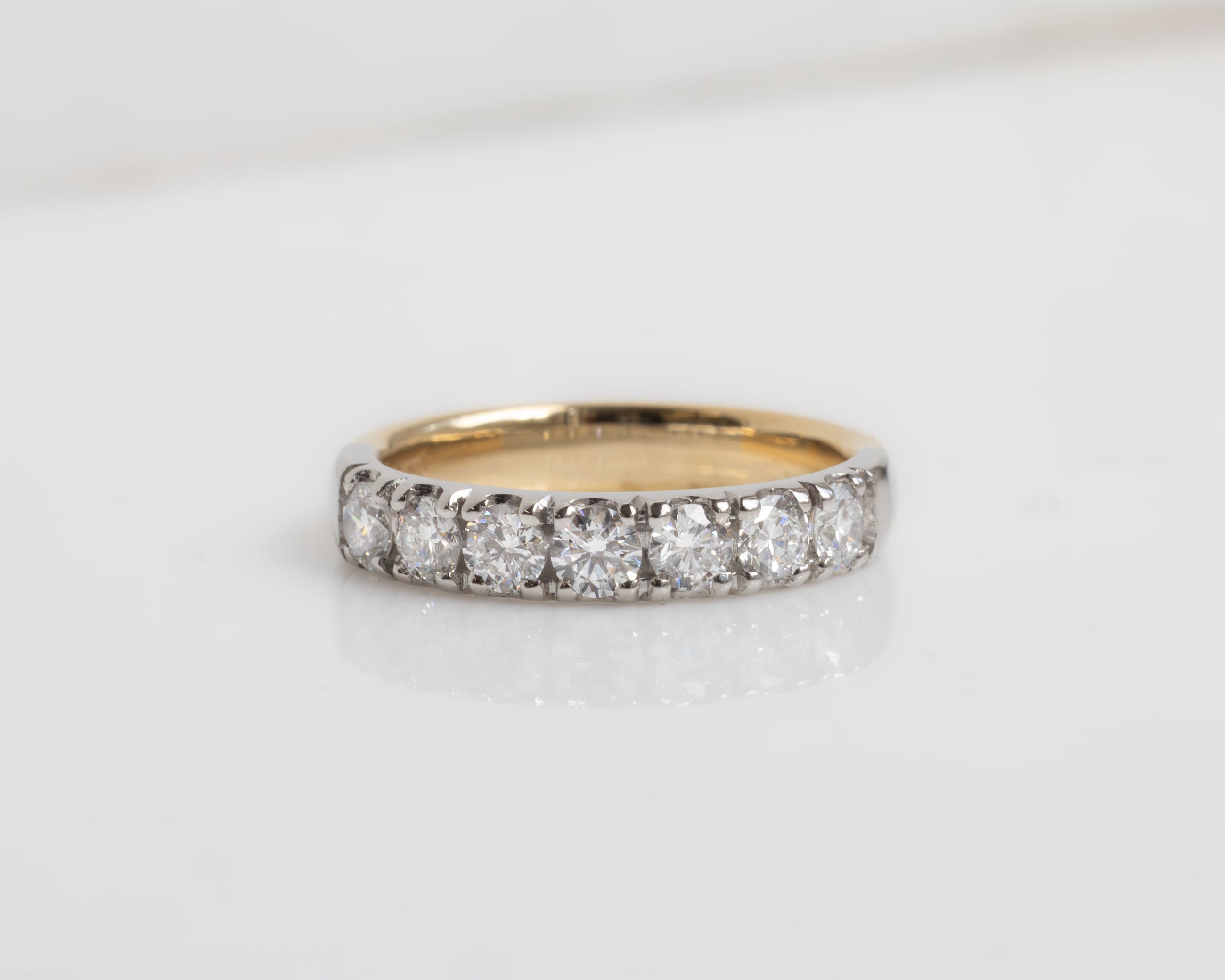 Gold ring with diamonds on a light gray background