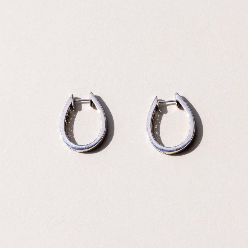 A pair of white gold hoop earrings with a row of round brilliant cut diamonds set across the hoop.