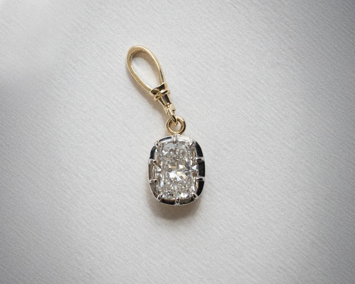A cushion cut diamond drop pendant in yellow gold