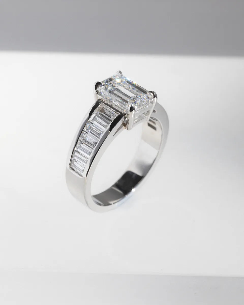 An emerald cut with baguette shoulders, in white gold