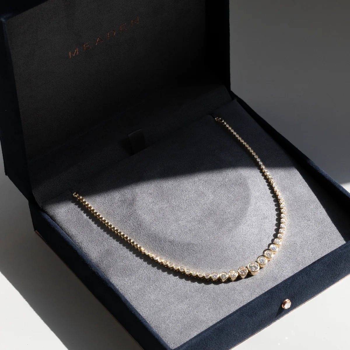 A graduated diamond tennis necklace in yellow gold